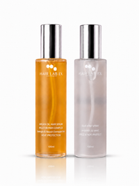 Two Hair Lab Ex hair care bottles on a white background: an amber oil hair serum on the left and a milky hair spray on the right, both with silver caps.